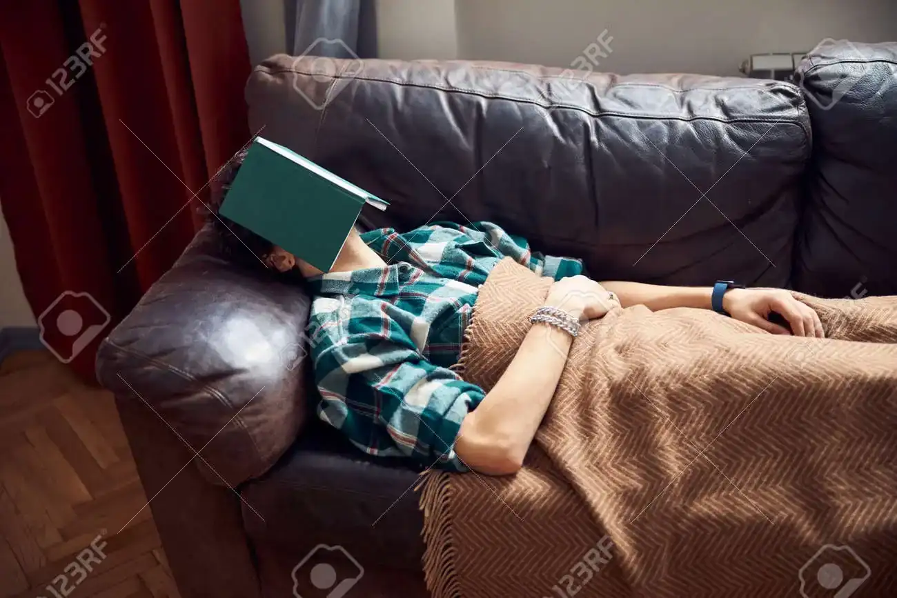 149334532-young-man-with-book-on-face-sleeping-on-sofa-at-home.webp