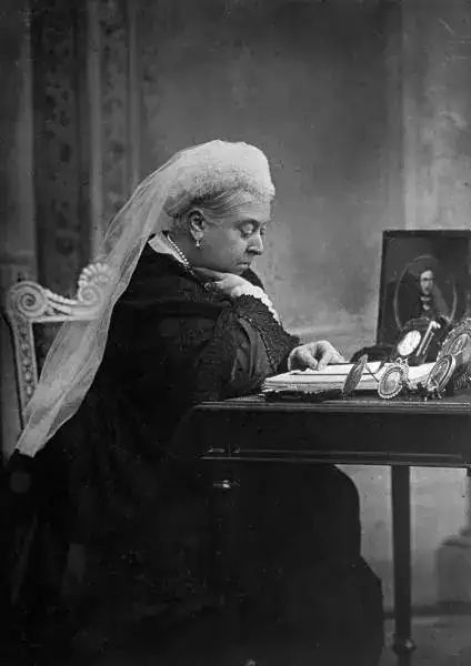 British monarch Queen Victoria seated at her writing desk. 1892.webp