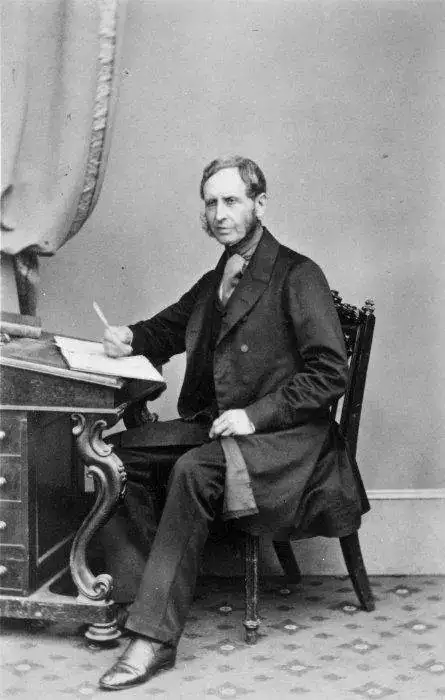 Captain Robert FitzRoy seated at a writing desk, circa 1860..webp