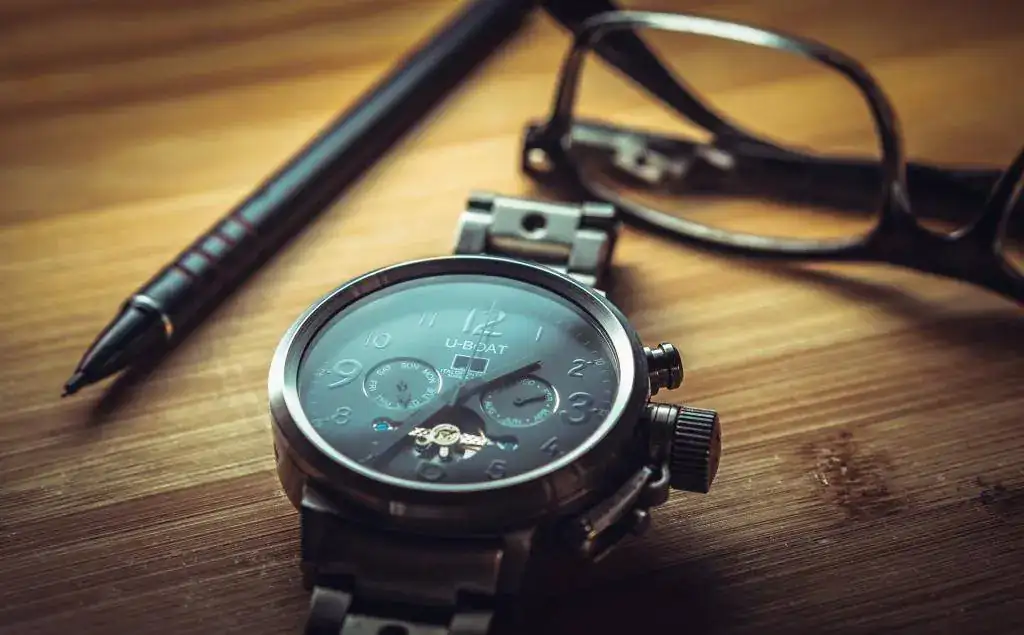 Clock_Glasses_Pen_Desk_Wooden_Table_Close_watch_time_1920x1191.webp
