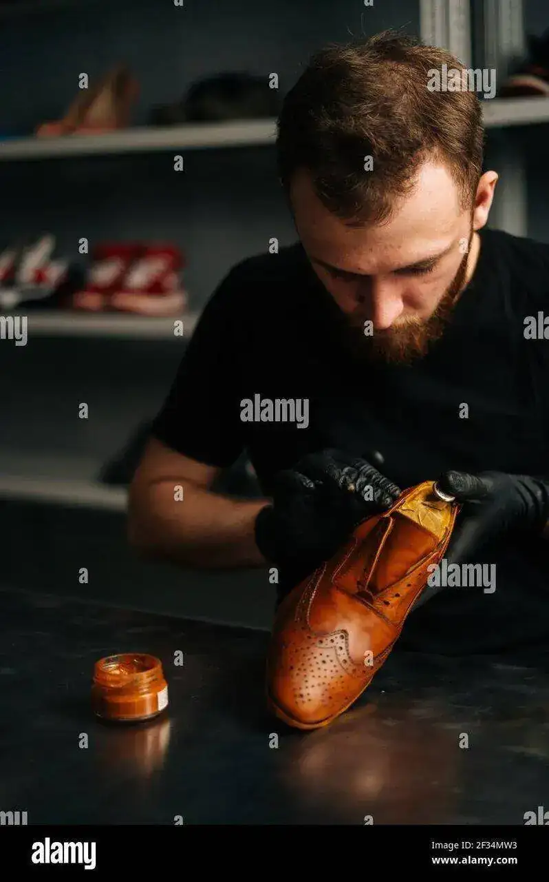 primer-plano-retrato-de-zapatero-con-guantes-negros-frotando-la-pintura-sobre-zapatos-de-cuer...webp