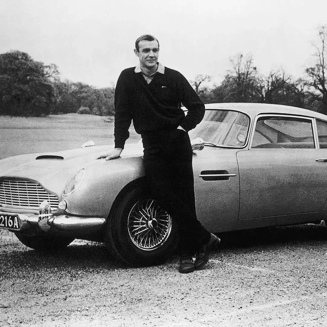 Sean Connery (James Bond 007) on the set of 'Goldfinger,' and his Aston Martin DB5.webp